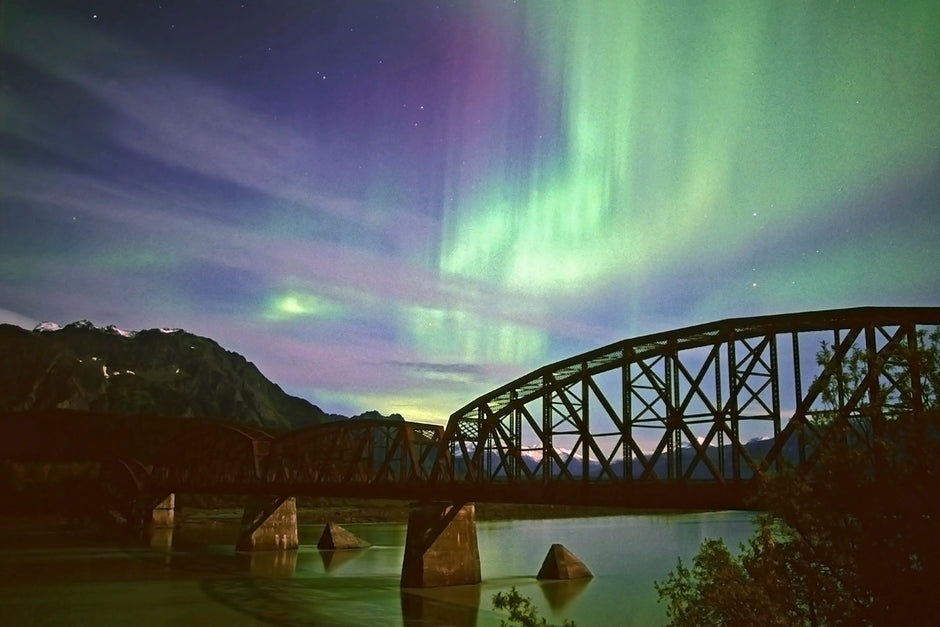 Aurora borealis arching over a frozen Alaska landscape like a bridge of light